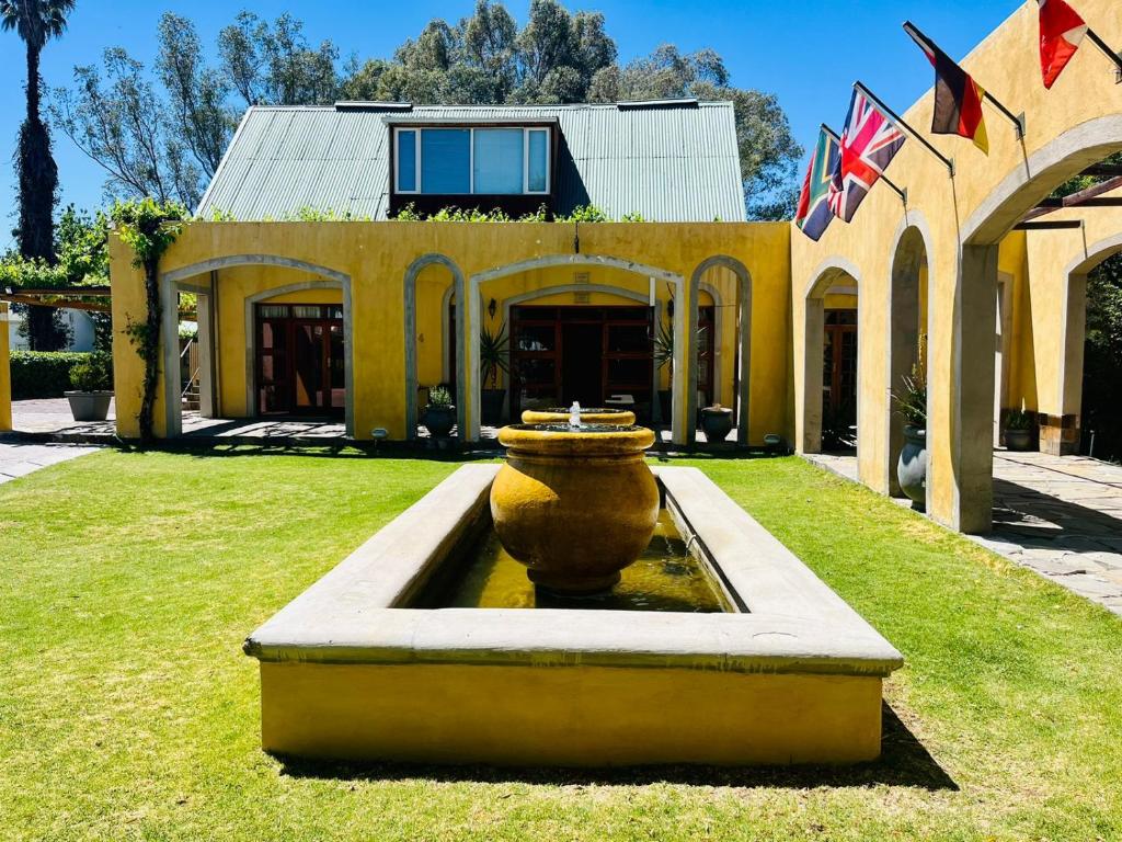 a large vase sitting in the grass in front of a building at 17 on Bird Guest House in Beaufort West