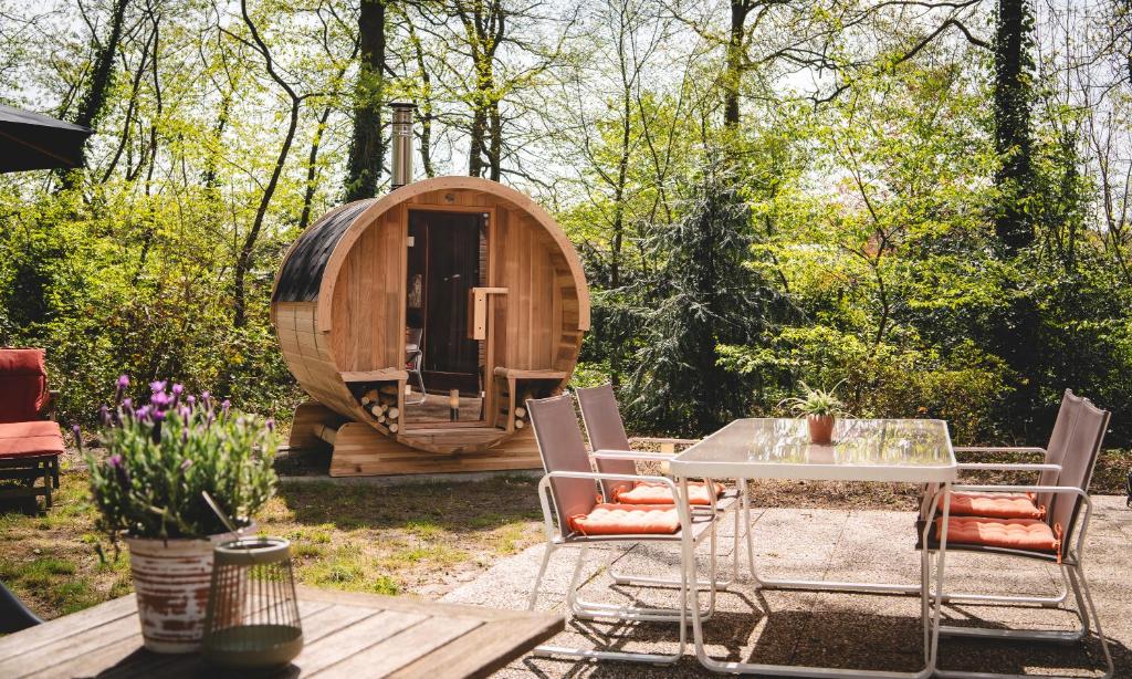 a table and chairs in front of a circular wooden cabin at Boshuisje Rekem - Ember in Lanaken