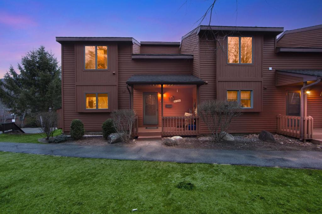 a brown house with a lawn in front of it at Otter Slide 78I - A Cozy Mountain Retreat in North Creek