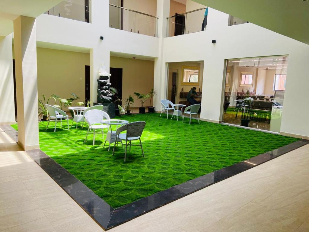 a room with a green floor with chairs and tables at Zip By Spree Hotels Neelam Nakshatra in Kudal