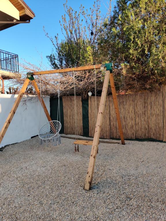 a wooden swing set in front of a fence at Daro tiny house in Vama Veche