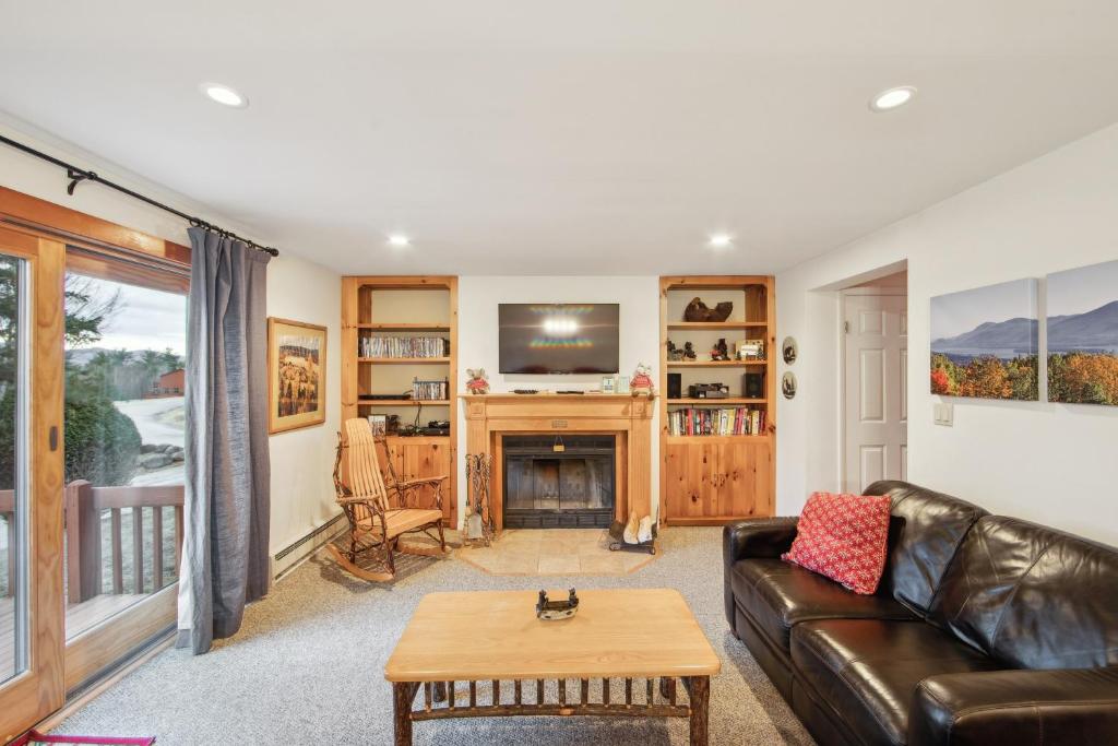a living room with a leather couch and a fireplace at Tahawus 74I - A Cozy Adirondack Retreat in North Creek