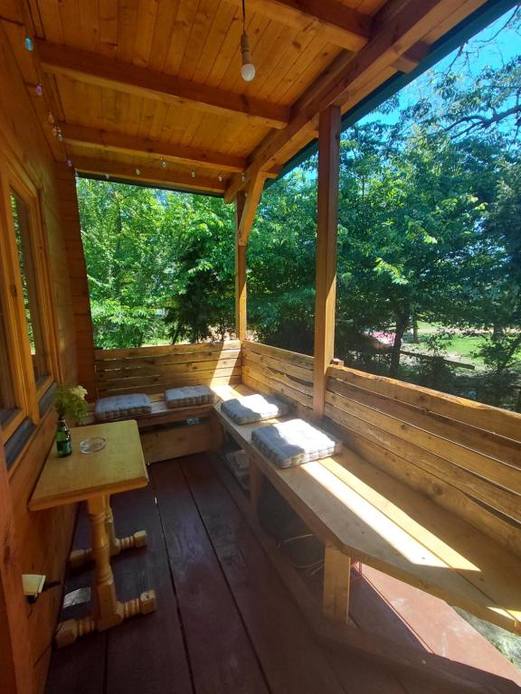 un portico di una cabina in legno con tavolo e panche di comjun a Ada