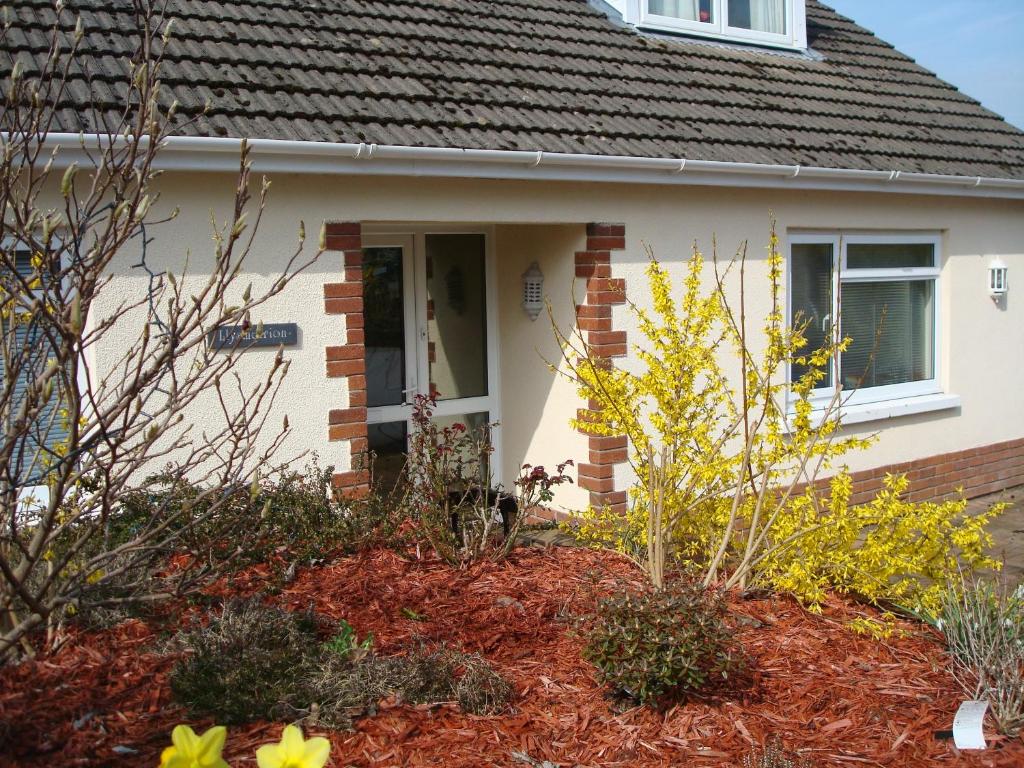 a small white house with a porch and flowers at Talybont B&B Aberystwyth in Talybont