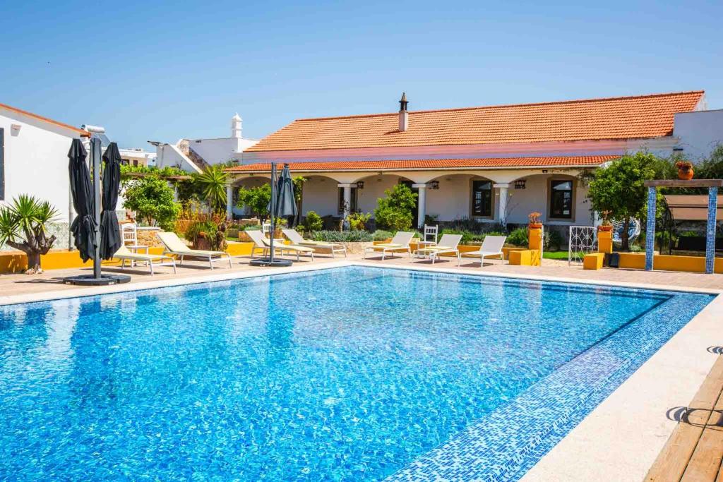 AlcariaにあるLuxury Farmhouse Albufeiraの椅子とパラソルのある大きなプール