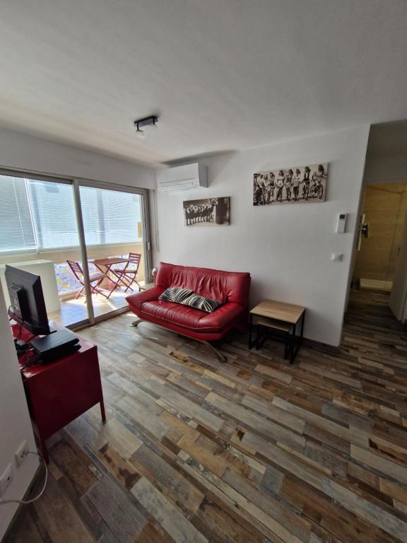 un salon avec un canapé rouge et une télévision dans l'établissement Life in red with parking and air conditioning, à Sète