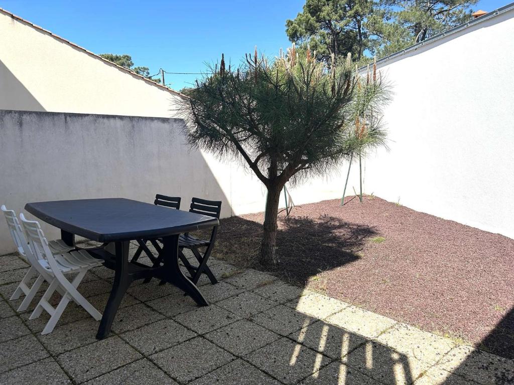 une table et des chaises assises à côté d'un arbre dans l'établissement Charmante maison proche plage, calme, terrasse, parking, accès forêt et pistes cyclables - FR-1-224-119, à Saint-Hilaire-de-Riez