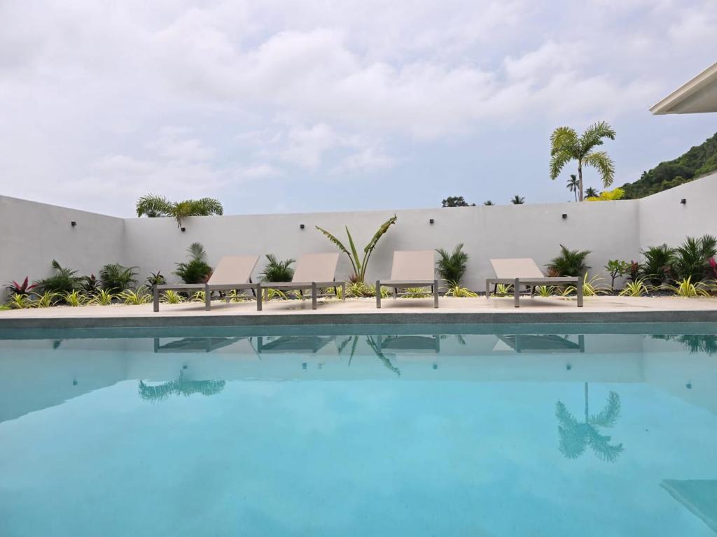 a pool with benches next to a white wall at Private villa near beach Koh Samui in Koh Samui