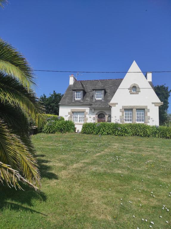 une grande maison blanche sur une colline avec un palmier dans l'établissement les lilas, à Paimpol
