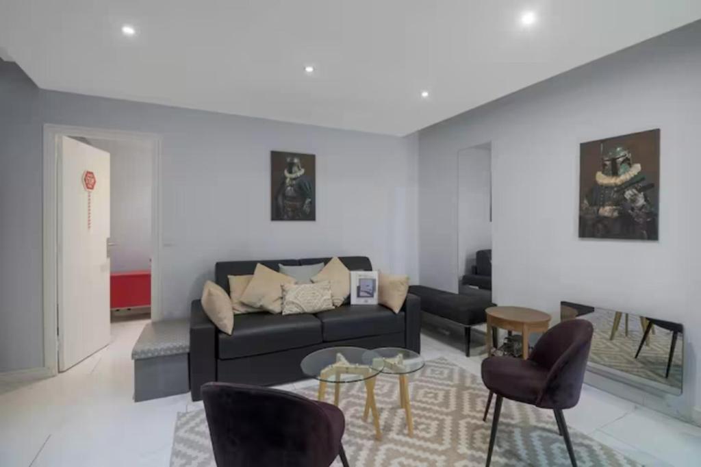 - un salon avec un canapé noir et des chaises dans l'établissement Appartement Popincourt Bastille, à Paris