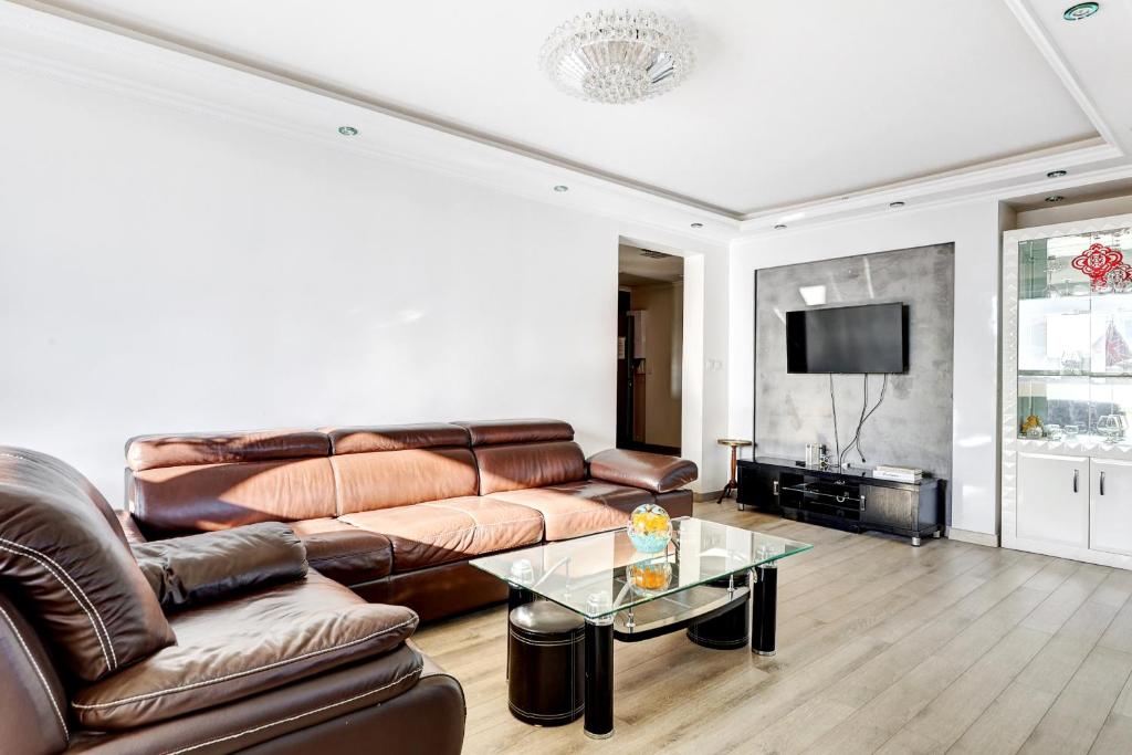a living room with a leather couch and a table at 100m2, Appartement Moderne et Luxueux 6 personnes in Bagnolet