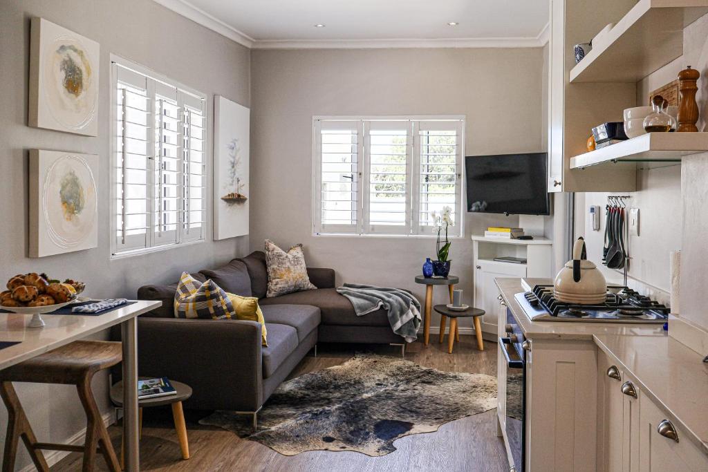 ein Wohnzimmer mit Couch und Küche in der Unterkunft C'estÇa Cottage Modern Luxurious Sounds of the Sea in Hermanus