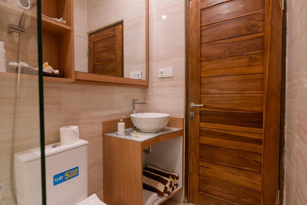 a bathroom with a sink and a wooden door at Mara inn in Nusa Dua