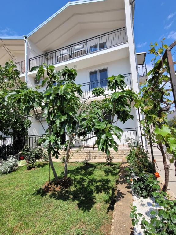 ein weißes Gebäude mit Bäumen davor in der Unterkunft N&M apartments in Vodice