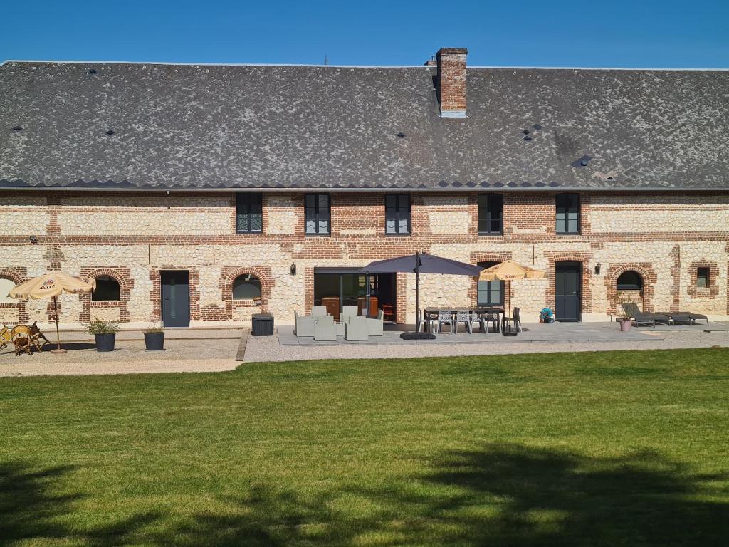 un grande edificio in mattoni con un patio con tavoli e ombrelloni di Le Domaine du Tronquoi. a Vironchaux