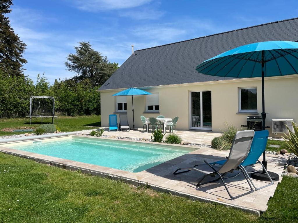 - une piscine avec un parasol bleu, une chaise et un parasol dans l'établissement Maison les coquelicots, à Garennes-sur-Eure