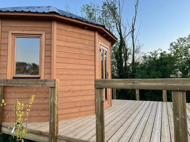 a small wooden cabin with a wooden deck at Camping à la ferme - Hébergements insolites in Cerisy-la-Forêt