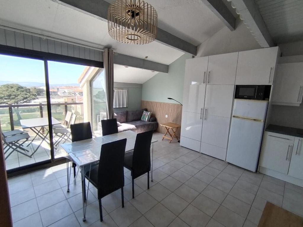 une cuisine et une salle à manger avec une table et des chaises dans l'établissement Appartement en bord d'étang, au Barcarès