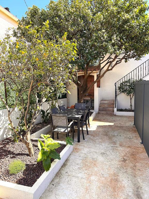 un patio avec une table et des chaises sous un arbre dans l'établissement Hébergement de Standing à la Mer avec bel extérieur, à Banyuls-sur-Mer