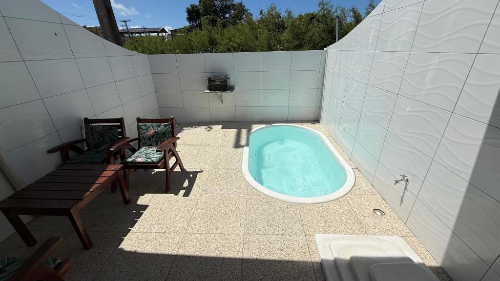 a bathroom with a tub and two chairs and a bench at Bangalô com tudo privativo em Tamandaré/PE in Tamandaré