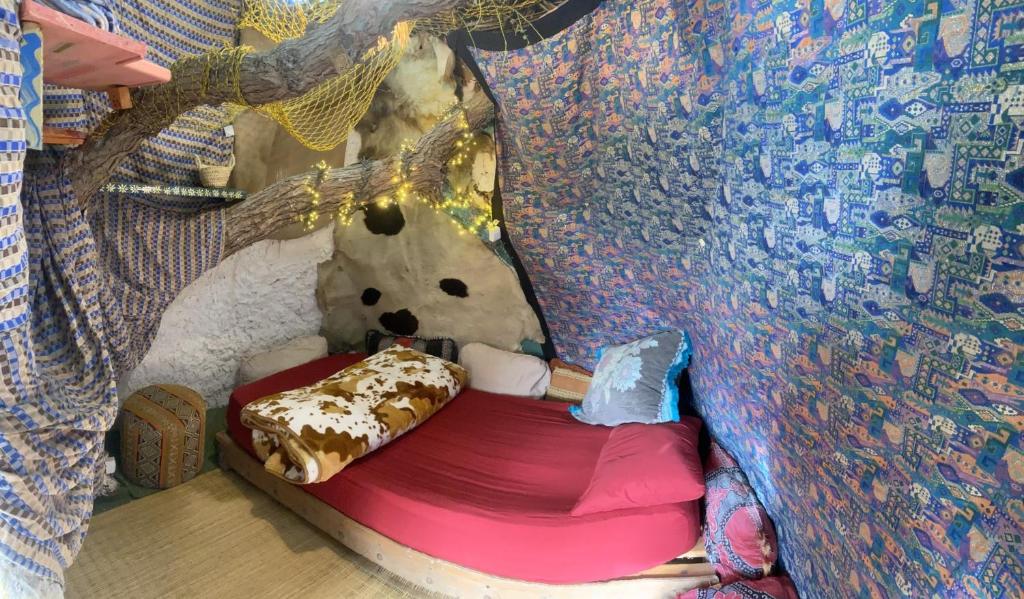 un orsacchiotto seduto in un letto in una stanza di Adam's Tree House ad Aourir