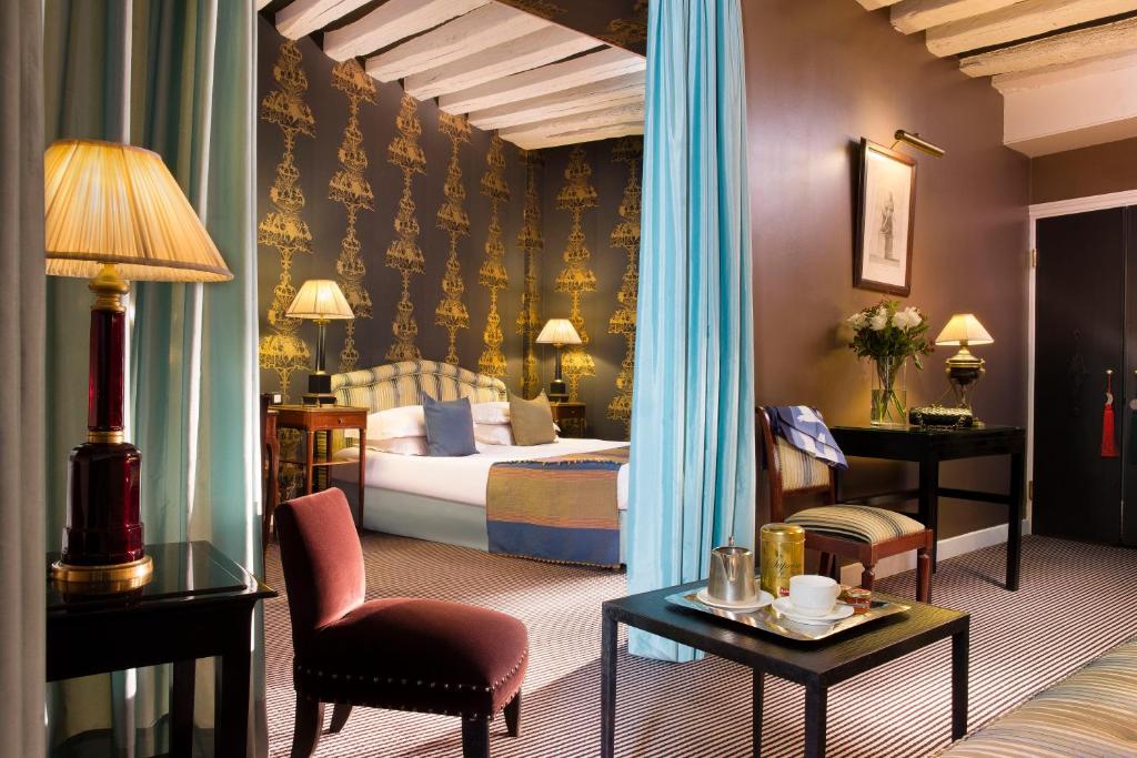 a hotel room with a bed, chair, table and lamps at Hotel Residence Des Arts in Paris