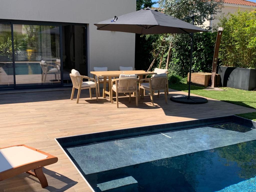un patio avec une table, des chaises et un parasol dans l'établissement Villa Meyzieu Grand Large, à Meyzieu