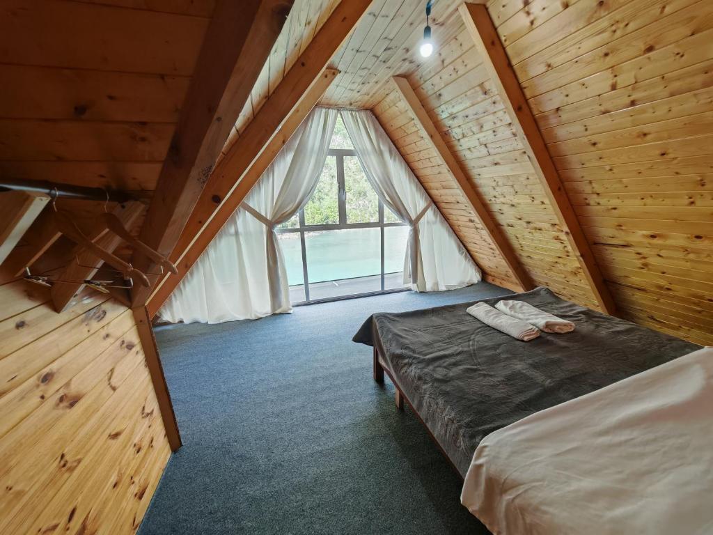 a bedroom with a bed in a wooden cabin at Riverside Komani Lake in Koman