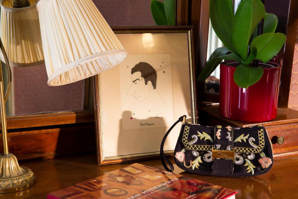 a table with a lamp and a picture and a purse at Hotel Residence Des Arts in Paris