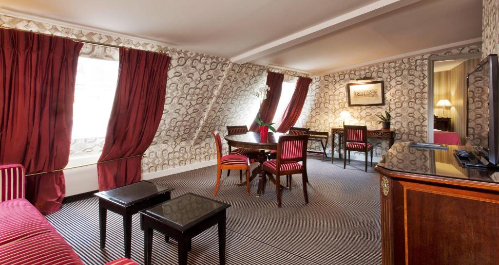 a living room with a red couch and a table and chairs at Hotel Residence Des Arts in Paris