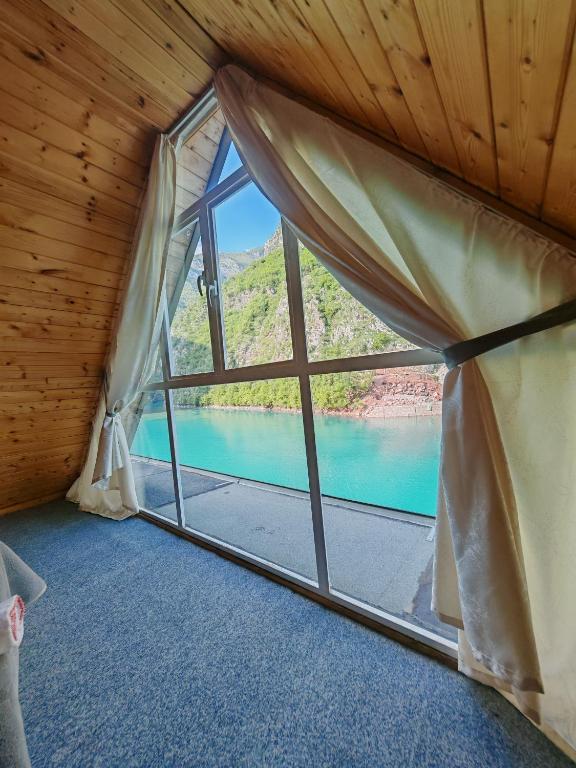a room with a window with a view of a lake at Riverside Komani Lake in Koman