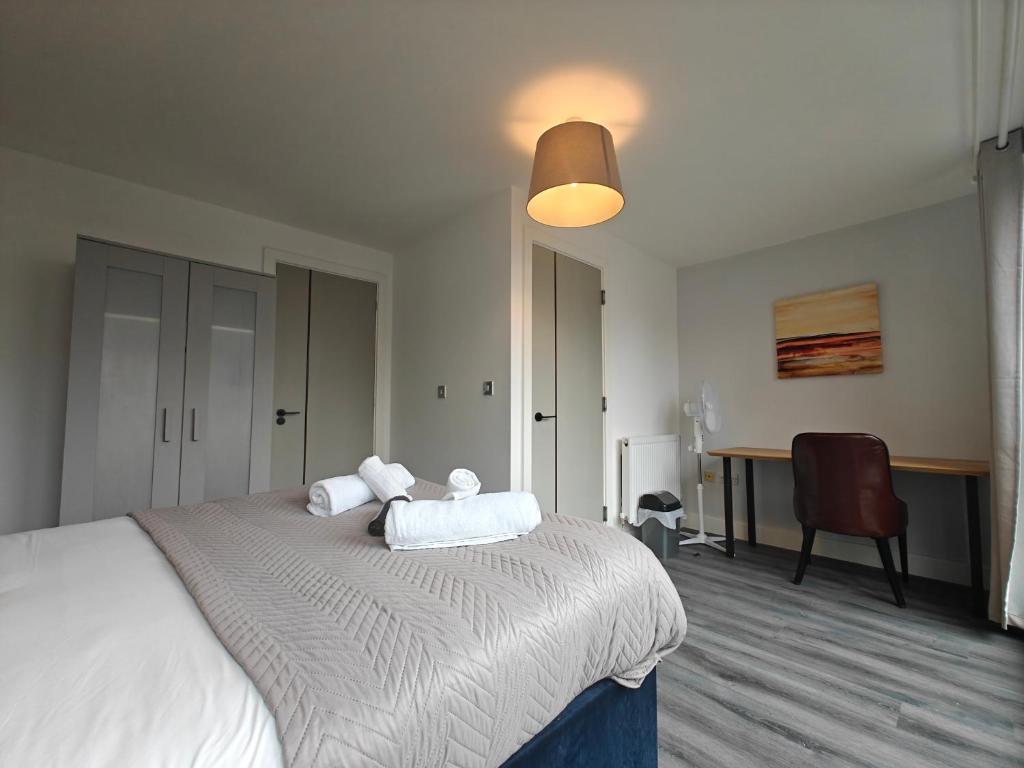 een slaapkamer met een bed met witte lakens en een bureau bij Park Central 4 Double Bedroom House in Birmingham City Center in Birmingham