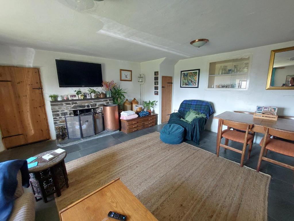 a living room with a tv and a table and a couch at Rural Historic Farmhouse - A Peaceful Escape in West Down