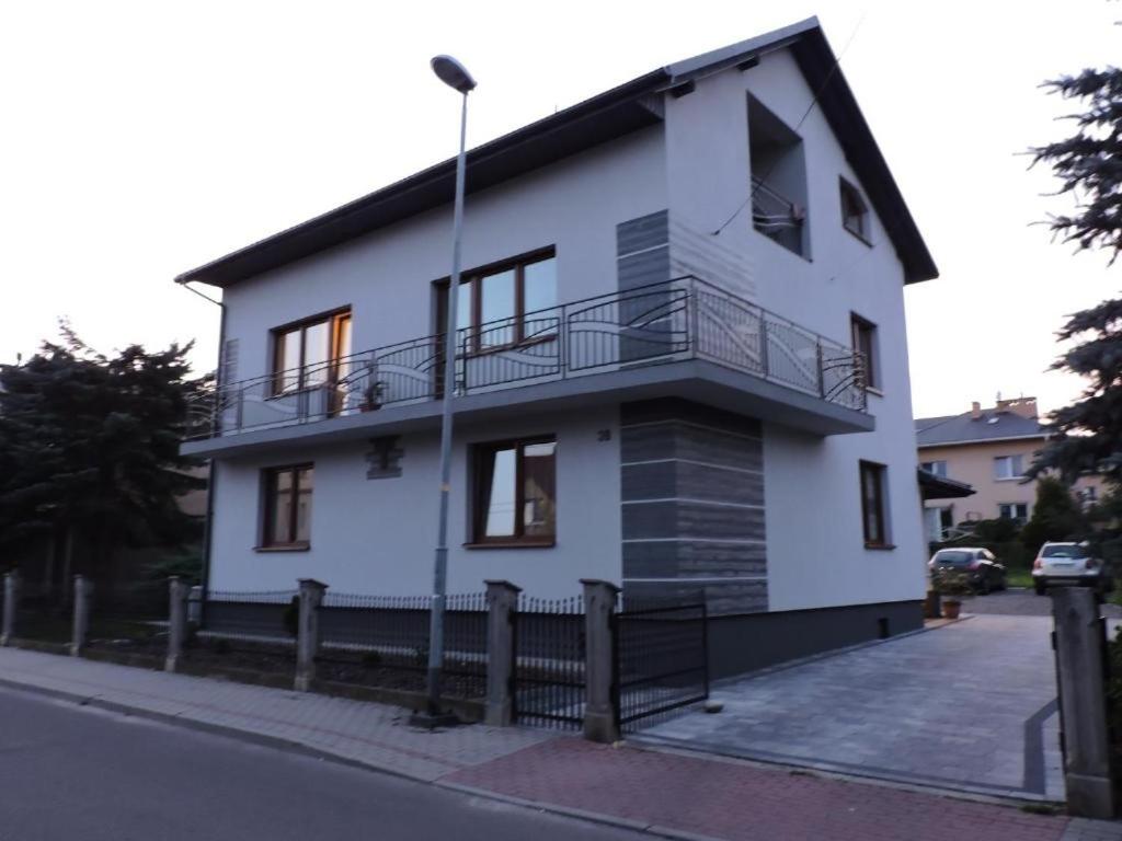 a white house with a balcony on a street at Apartament Mączyńskiego 4 in Jarosław