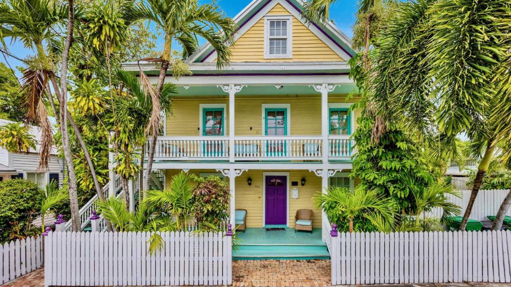 una casa gialla con una porta viola e palme di Barbuda Suite by Last Key Realty a Key West