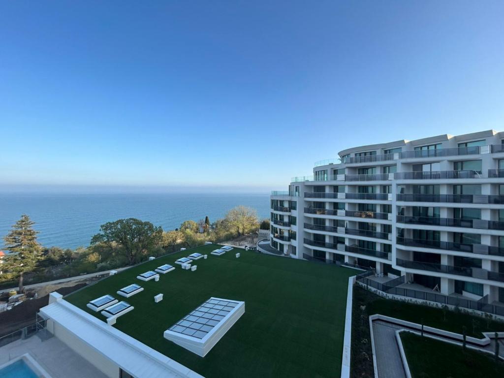 a large apartment building with a green lawn in front of the ocean at Skyline studio 44 in Varna City