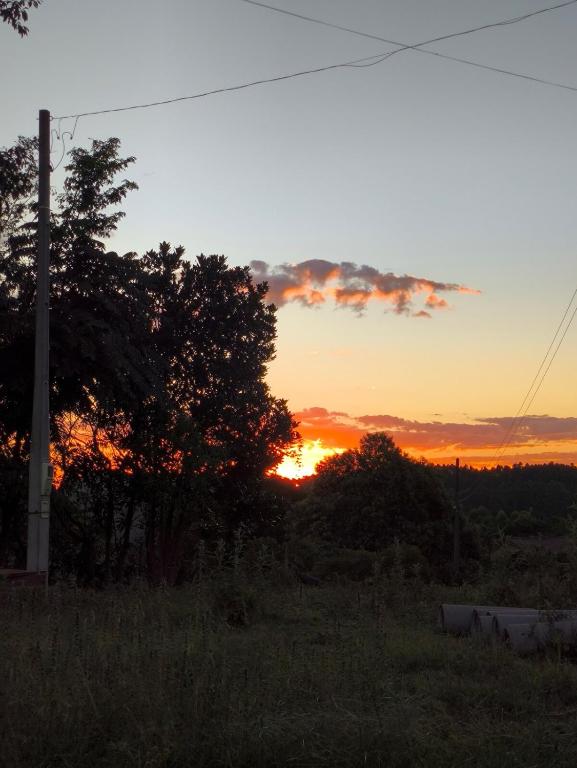a sunset in a field with trees and a pole at Casa de campo da Prof Fabi in Montenegro