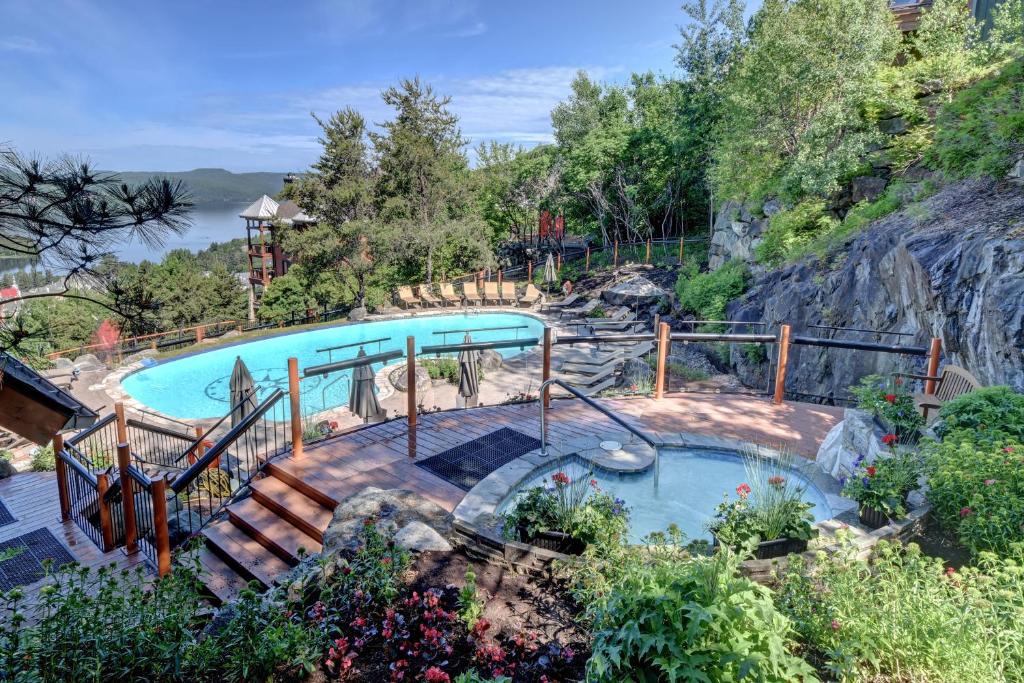 une piscine avec un escalier à côté d'une colline dans l'établissement Equinox Condo On-Resort Luxury Direct Ski Access Stunning View, à Mont-Tremblant