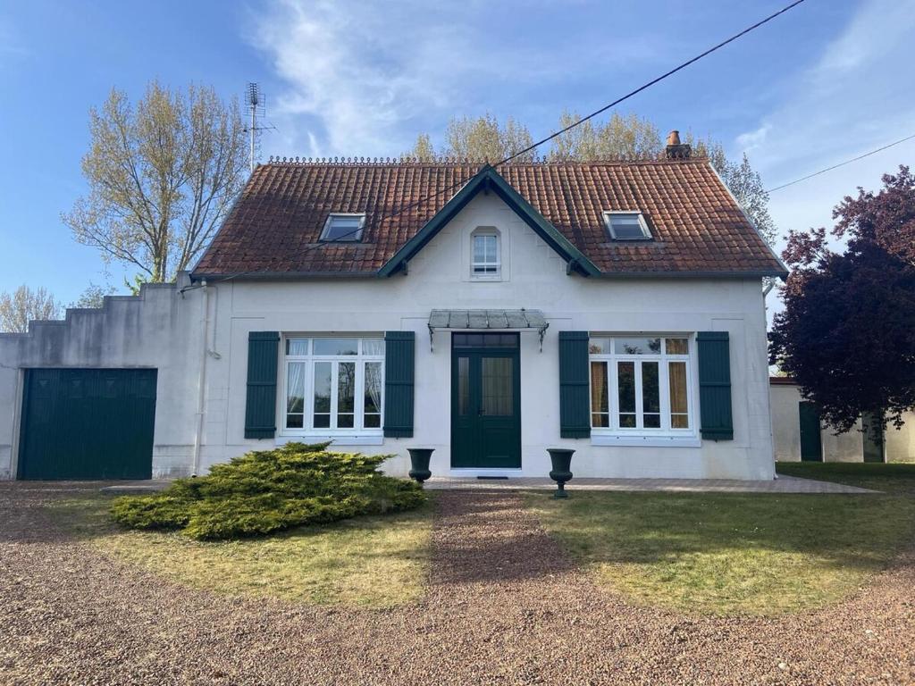 a white house with a green door and a yard at Mer et Campagne, maison entourée d'un jardin privé in Quend
