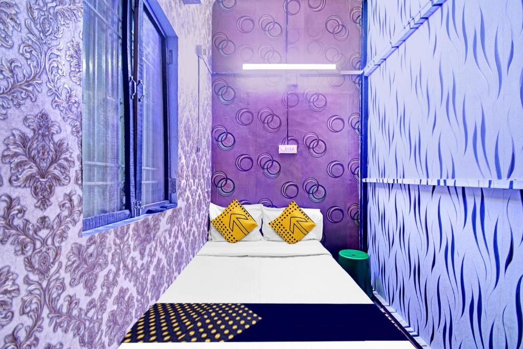 a room with purple walls and a bed with yellow pillows at Hotel O Mo Kudia in Brahmapur