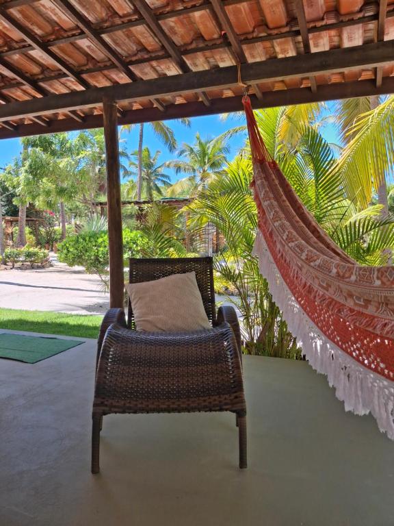 a wicker chair with a pillow in a hammock at Recanto Verde - Praia de Santo Antônio in Diogo