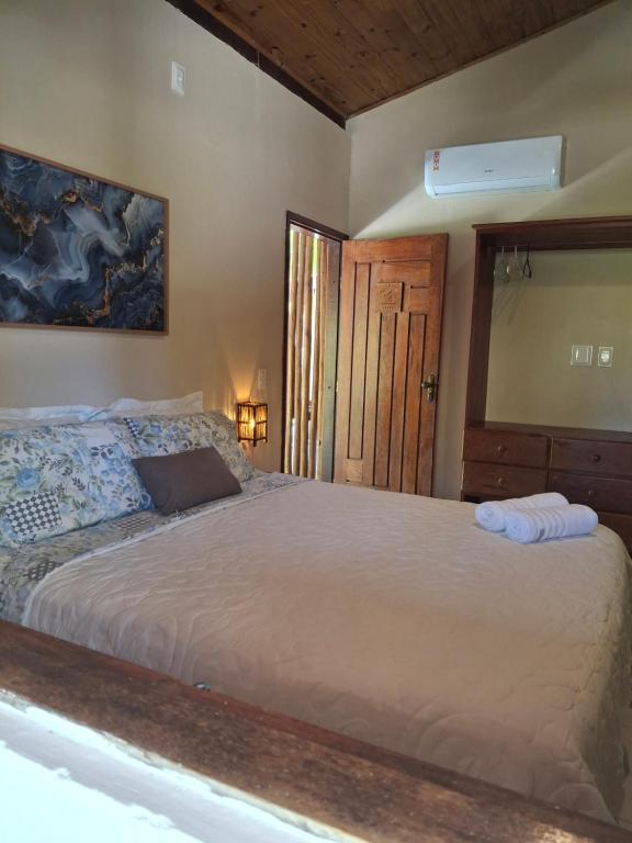 a bedroom with a large bed and a mirror at Recanto Verde - Praia de Santo Antônio in Diogo