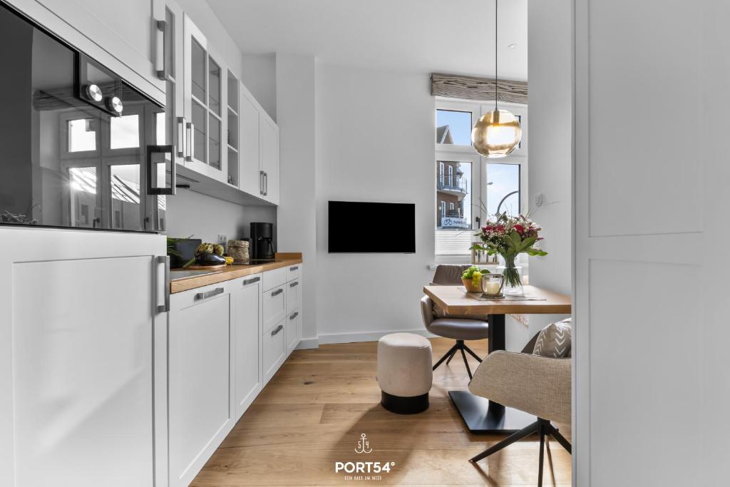 a kitchen with white cabinets and a dining room with a table at Ferienwohnung Kleine Welle Westerland auf Sylt in Westerland (Sylt)
