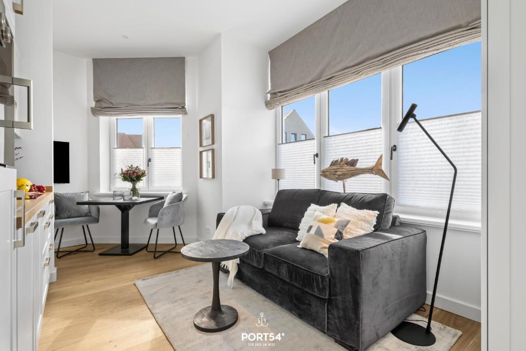 un salon avec un canapé noir et une table dans l'établissement Ferienwohnung Leichte Brise Westerland auf Sylt, à Westerland