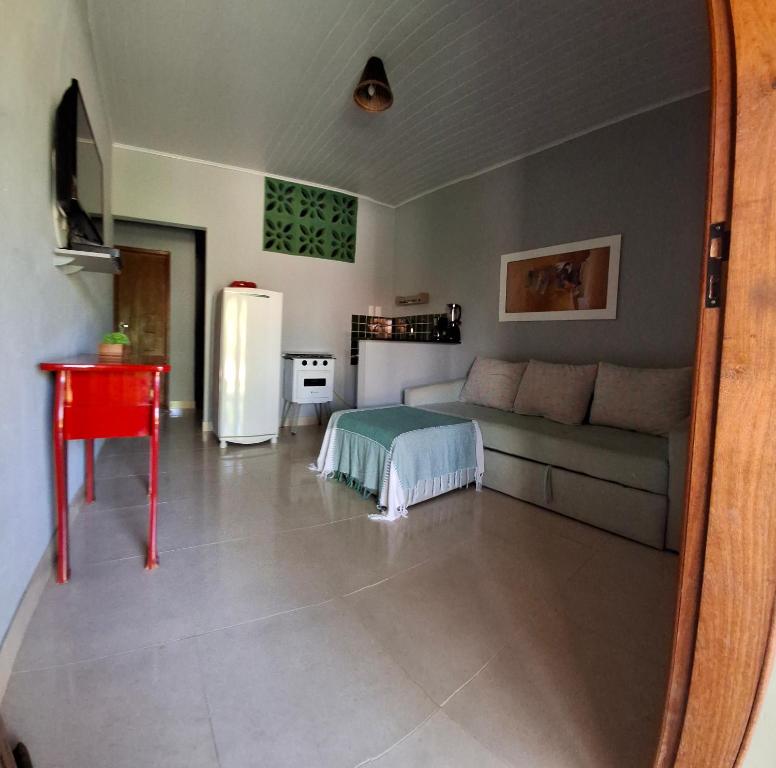 a living room with a couch and a refrigerator at Recanto Verde - Praia de Santo Antônio in Diogo
