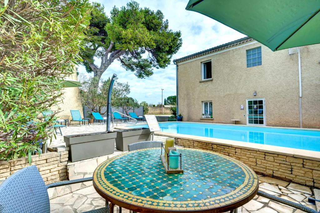 a patio with a table and chairs and a pool at Logis Hôtel La Bastide d'Entraigues in Entraigues-sur-la-Sorgue