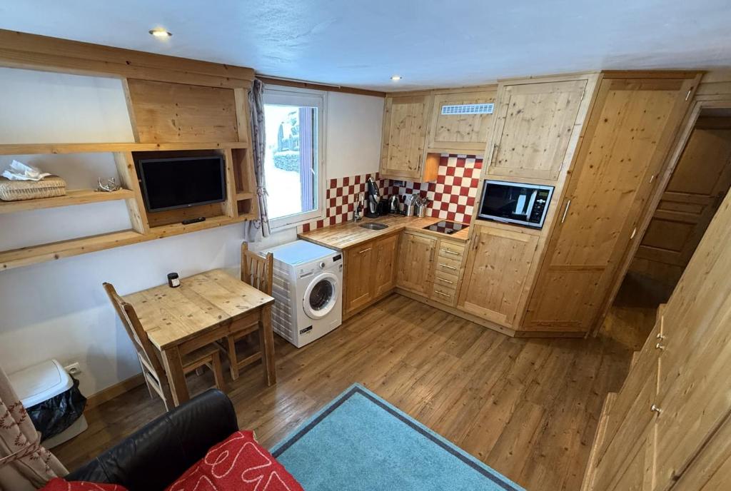 - une cuisine avec des placards en bois, une table et un four micro-ondes dans l'établissement Le Nid Douillé du Crêt, parking et terrasse, à Val dʼIsère