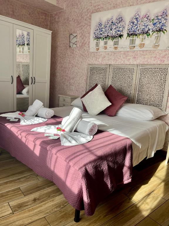 a bedroom with a large bed with purple and white sheets at Paganino rooms in Fiumicino