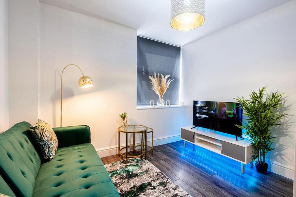 a living room with a green couch and a tv at Central Apartment - Sheffield in Sheffield