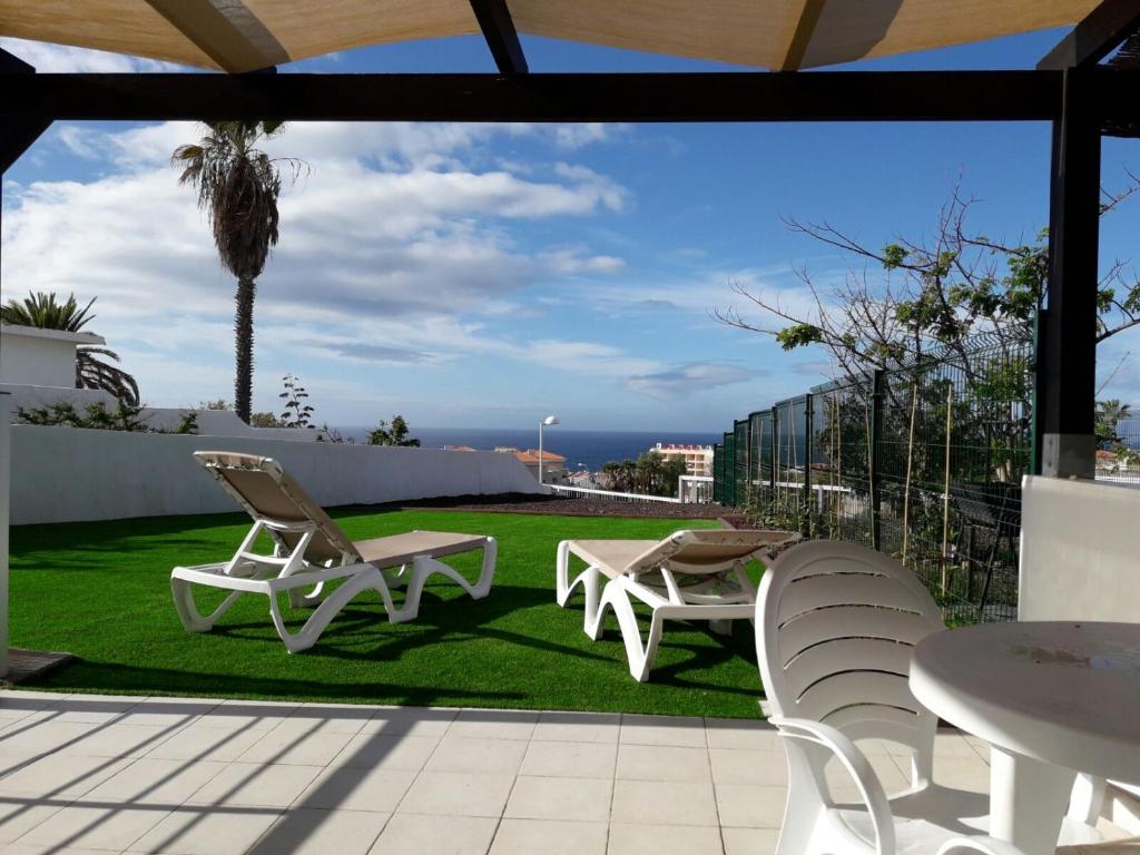 a patio with two chairs and a table and a lawn at Sunset view duplex in Callao Salvaje